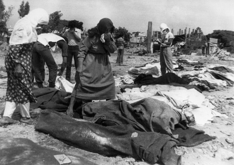 Palestinian, holding handkerchiefs to their faces, look for the bodies of relatives, victims of the Sabra-Shatila massacre in the Palestinian refugee camps in Beirut on Sept. 16-18, 1982.