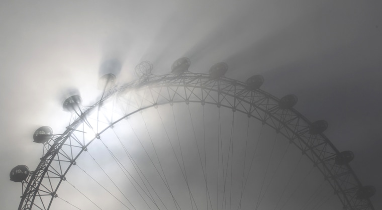 The pods on the London Eye tourist attraction cast shadows against a thick morning fog as the spring sun shine begins to burn it off in central London...