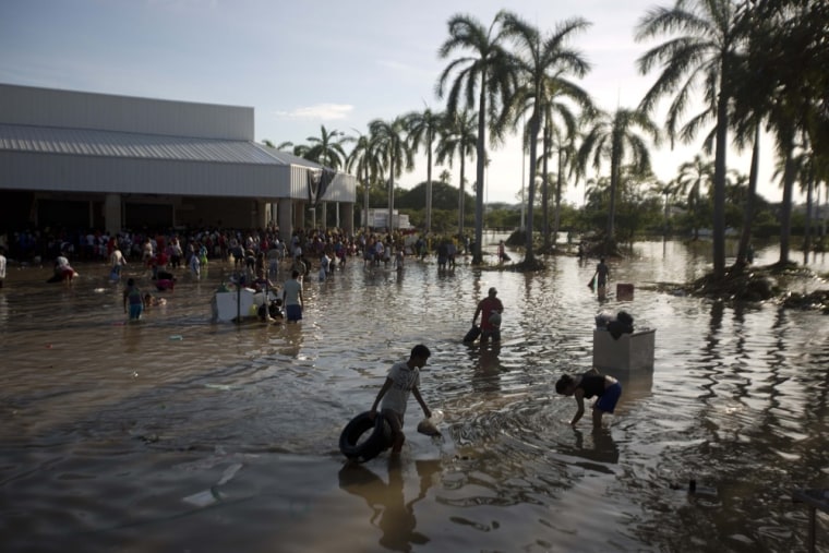 People wade through waist-high water in a store's parking, looking for valuables, south of Acapulco, in Punta Diamante, Mexico, on Sept. 18. Mexico was hit by the one-two punch of twin storms over the weekend, and the storm that soaked Acapulco on Sunday - Manuel -re-formed into a tropical storm Wednesday, threatening to bring more flooding to the country's northern coast. With roads blocked by landslides, rockslides, floods and collapsed bridges, Acapulco was cut off from road transport.