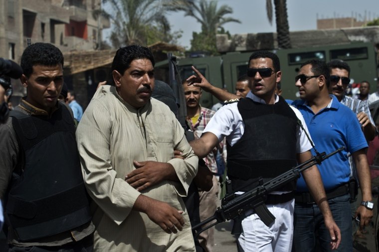 Armed policemen arrest a man during a raid in Kerdasa.