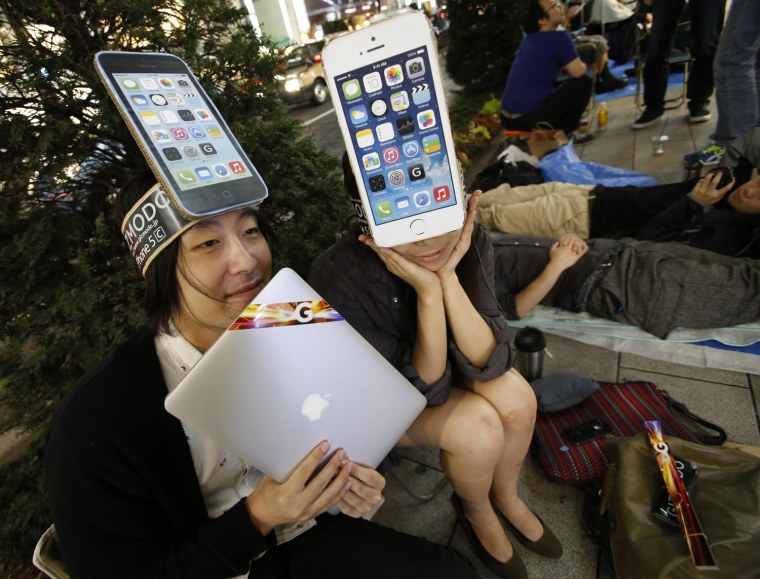 A man and a woman wearing cardboard hats depicting Apple's new iPhone 5C pose for photos as they wait for the release of Apple's new iPhone 5S, near the Apple Store at Tokyo's Ginza shopping district Sept. 19, a day before the iPhone 5S go on sale.