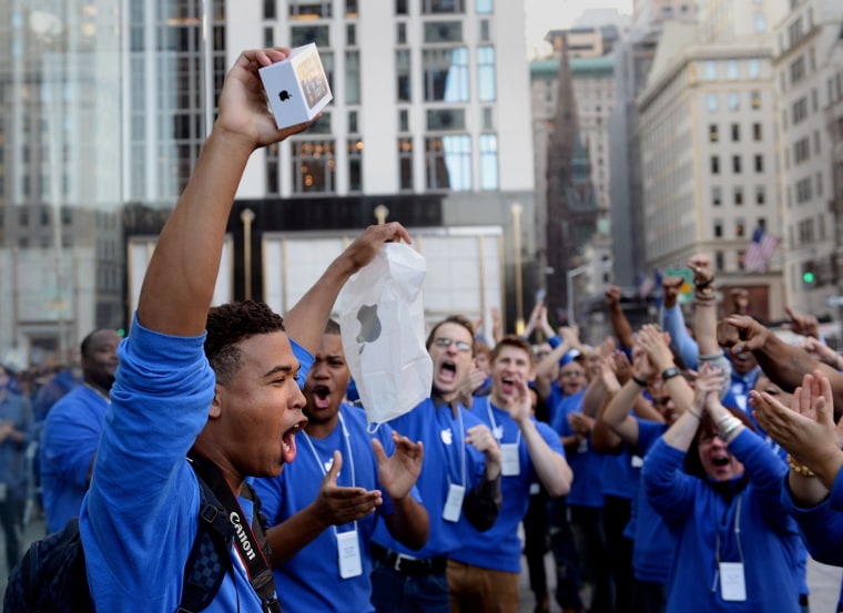 Brian Ceballo, left, emerges from the Apple Store on Fifth Avenue as the first to purchase the new iPhone 5 to the cheers of Apple store employees Sept. 20, in New York. Ceballo and a friend waited for fifteen days in line outside the store to be the first to buy the phone.