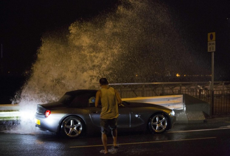 A man tries to get back into his car as a wave surges past a barrier on the shore during Typhoon Usagi in Hong Kong on Sept. 22.