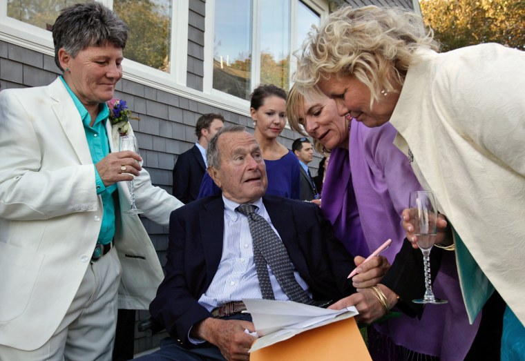 Former President George H.W. Bush prepares to sign the marriage license of longtime friends Helen Thorgalsen, right, and Bonnie Clement, left, in Kennebunkport, Maine, as officiant Nancy Sosa, third right, and Helen's daughter Lindsey, rear, look on.