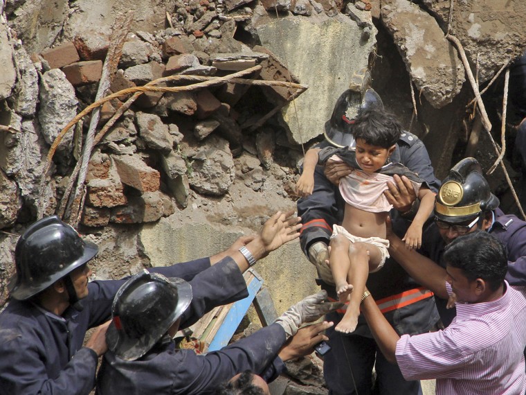 Indian fire officials rescue a girl Friday from debris of a collapsed building in Mumbai, India.