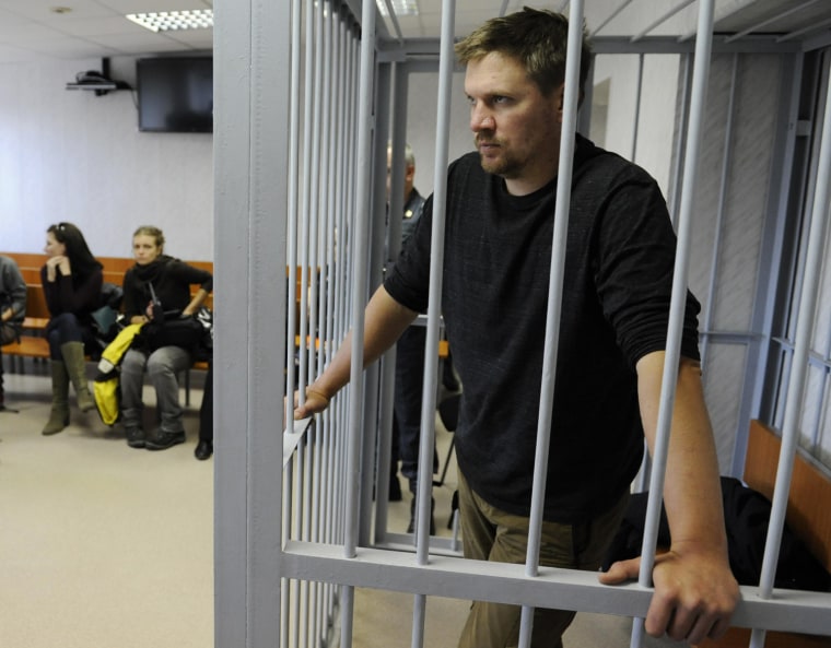 Greenpeace activist Anthony Perrett from Britain looks out from a defendants' box at a district court in Murmansk September 29, 2013. A Russian court ordered 20 Greenpeace activists from around the world to be held in custody for two months pending further investigation over a protest against offshore oil drilling in the Arctic, drawing condemnation and a vow to appeal. In proceedings that Greenpeace said evoked Soviet-era scare tactics, activists from a ship used in the protest at an oil rig were led to court in the port of Murmansk in handcuffs and held in cages for a series of hearings that ended early on Friday.