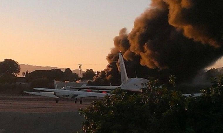 Smoke from a plane crash billows from behind other planes at the Santa Monica Airport on Sunday evening Sept. 29, 2013.
