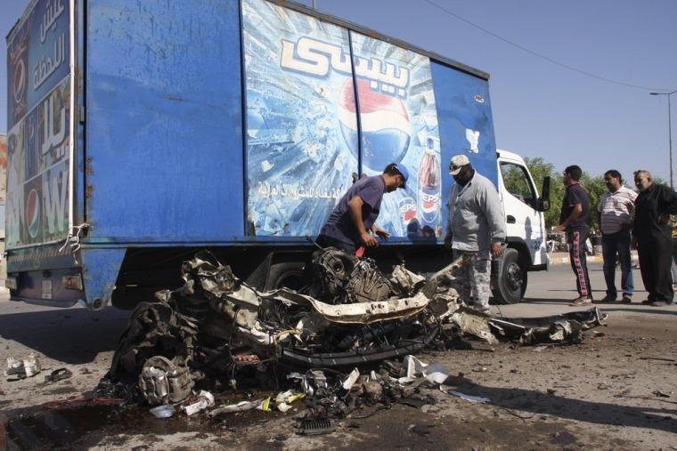 Residents inspect the mangled remains of a vehicle at the site of a car bomb attack in Baghdad's Sadr City on Monday.