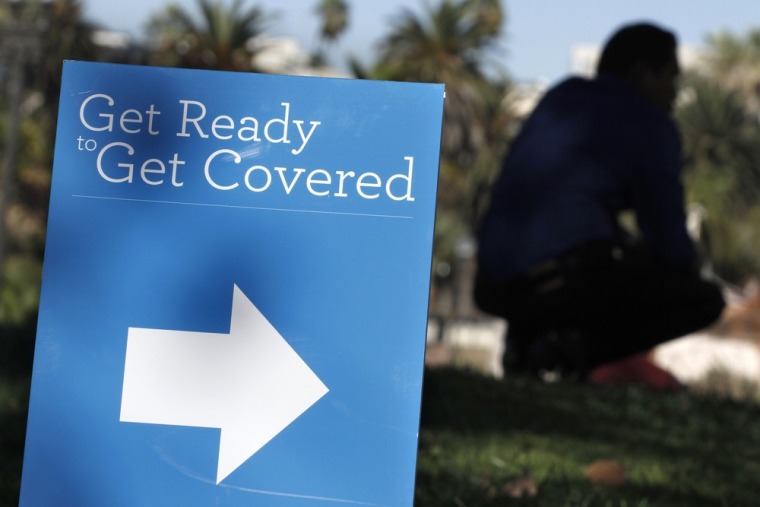 A man is silhouetted behind a sign at an Affordable Care Act outreach event hosted by Planned Parenthood for the Latino community in Los Angeles, Cali...