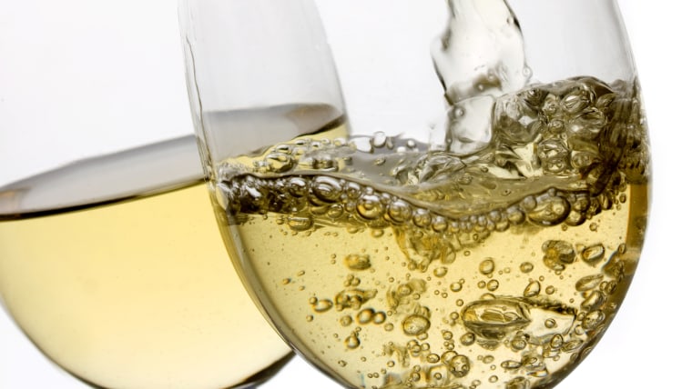 White wine poured in a glass over white background