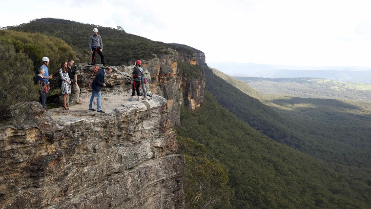 Britain's Prince William (C) looks over the edge of a cliff as he and his wife Catherine, the Duchess of Cambridge, visit the Narrow Neck Lookout and ...