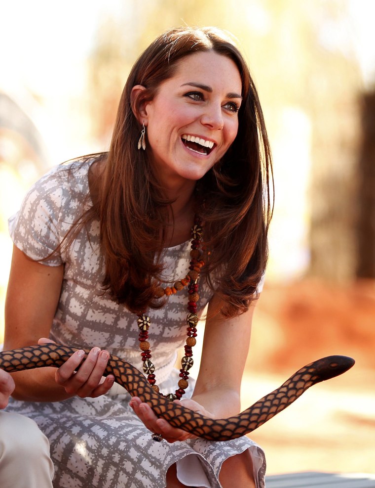 Britain's Catherine, Duchess of Cambridge, laughs as she holds a carved wooden snake during a visit to a local cultural centre at Uluru April 22, 2014...