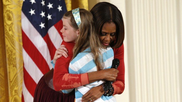 First Lady Michelle Obama hugs Charlotte Bell, 10, who gave the first lady her father's resume and said he had been out of work for three years, as Mi...