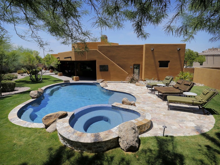 This is an exterior view of a luxury custom home with a listing price of $1 million on Wednesday, July 30, 2014, in Mesa, Ariz. The more than 4,000-square-foot home has a resort-style back yard, pool and hot tub, four bedrooms, three full and one partial bathrooms, a gourmet kitchen and travertine tile throughout the home.