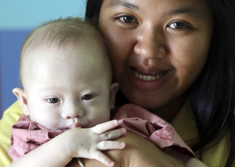 In this photo taken Aug. 3, 2014, Thai surrogate mother Pattaramon Chanbua, a 21-year-old food vendor, poses with Gammy, a nine-month old baby boy who...