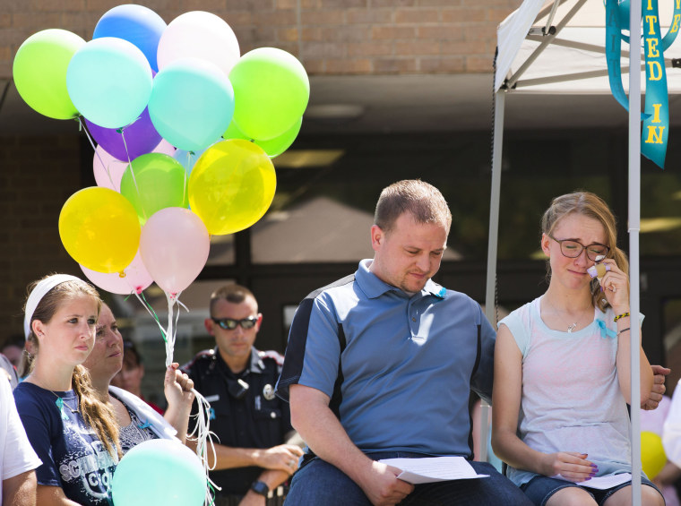 Cassidy Stay, right, the lone survivor of a family massacre in Texas, wipes her eyes as she sits next to her uncle Drew Lyons during a community memor...