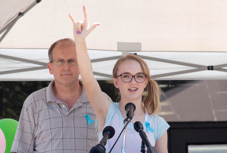 Cassidy Stay stands with her grandfather Roger Lyon on July 12, 2014 as she addresses the crowd at a memorial service for her six family members murdered in their home in Spring, Texas. Cassidy survived with gunshot wounds to her head and hand.