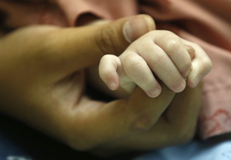 epa04340341 A Thai surrogate mother, Pattharamon Janbua (L), 21, holds the hand of her seven-month-old Down's Syndrome baby, Gammy or Naruebet Minchar...