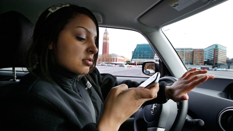 New driver Brandi Eadie, 16, looks down at her cell phone to read a text message as she drives through a rubber-cone course in Seattle on Wednesday, J...