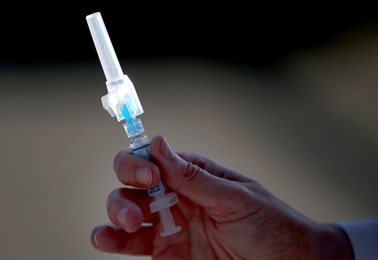 A nurse holds a syringe filled with flu vaccine during a drive-thru flu shot clinic at Doctors Medical Center