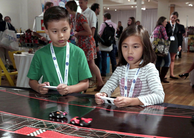 In this Oct. 1, 2014 photo, Evan and Jillian, of EvanTubeHD, test the Anki Drive battle-racing game, at the TTPM Holiday Showcase, in New York, Wednes...