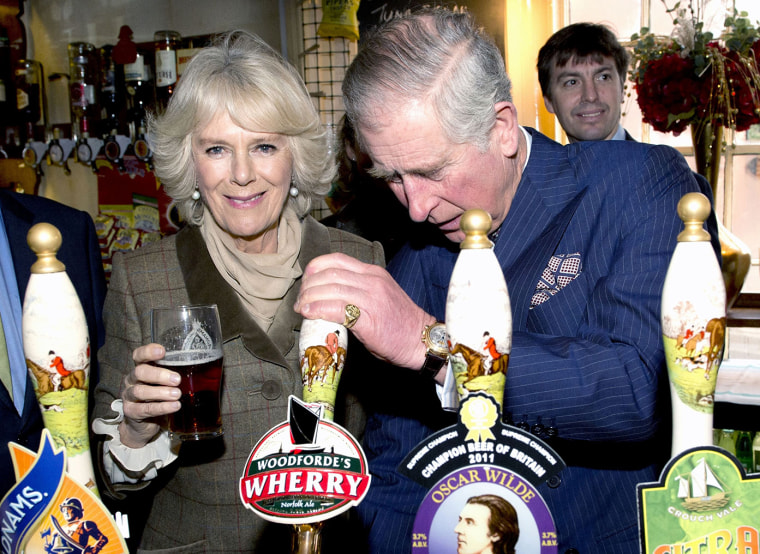Prince Charles pulls a pint of draught beer as Camilla looks on during a visit to The Bell pub.