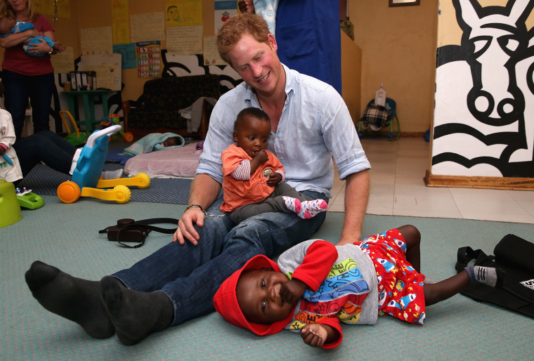 MOKHOTLONG, LESOTHO - DECEMBER 08:  Prince Harry plays with two young children (who are going through a programme for malnourishment) during a visit t...