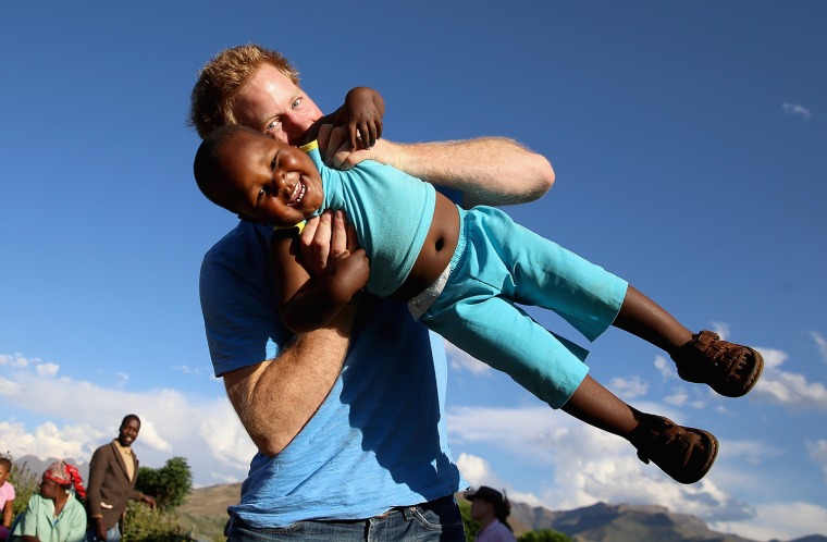 PITSENG, LESOTHO - DECEMBER 06:  Prince Harry swings young three year old orphan boy called Lerato in this photograph taken with the help of a three y...