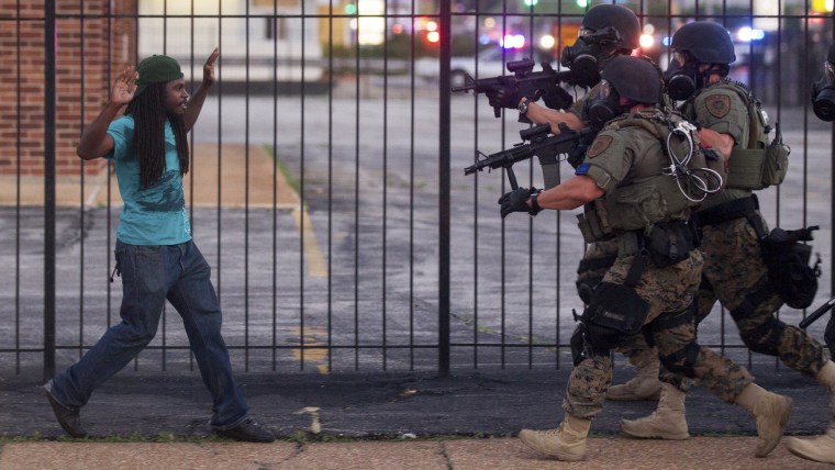 A man backs away as law enforcement officials close in on him and eventually detain him during protests over the death of Michael Brown, an unarmed black teenager killed by a police officer, in Ferguson, Mo., Aug. 11, 2014.