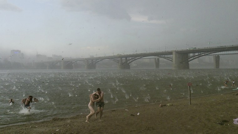 In this photo taken on a smartphone on July  12, 2014, people run to shelter from hailstorm on the beach at Ob River, the major river in western Siberia in Novosibirsk, Russia.