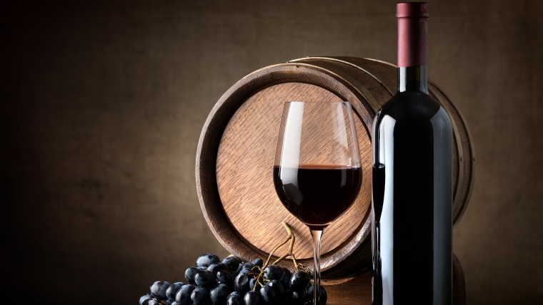 Bottle of red wine, grapes and wooden barrel