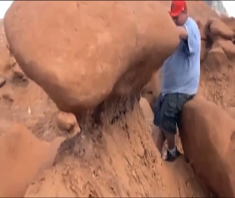 This frame grab from a video taken by Dave Hall shows a Boy Scouts leader looking over an ancient Utah desert rock formation at Goblin Valley State Park, which he later knocked down.