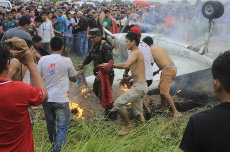 Bystanders and a soldier try to extinguish the fire on an Aerocon airliner after it crashed near the airport in Riveralta, Beni province, Bolivia, on Sunday.