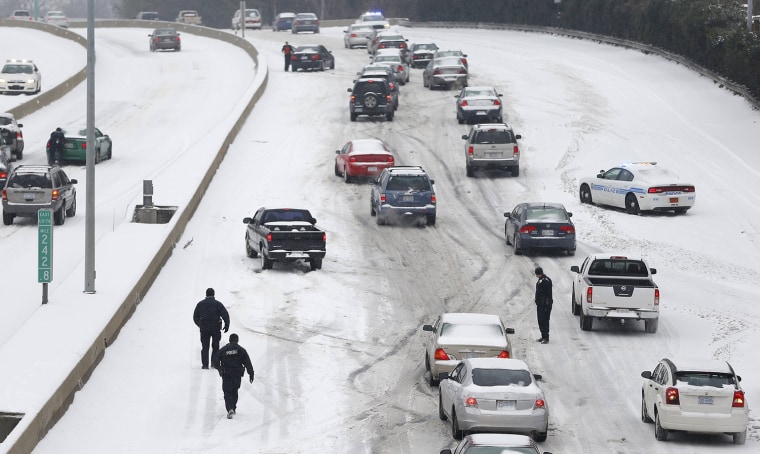 Charlotte Mecklenburg Police Officers work to assist motorists as they attempt to drive up a hill that is covered in snow in Charlotte, North Carolina...