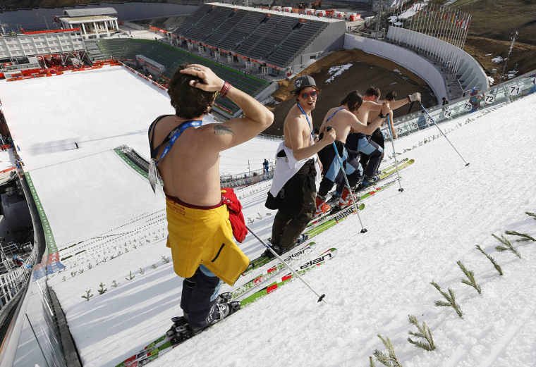 Feb. 10, 2014 - Sochi, Russia - Course workers take off their shirts to enjoy the warm weather as they prepare the landing hill before the Men's Nordi...