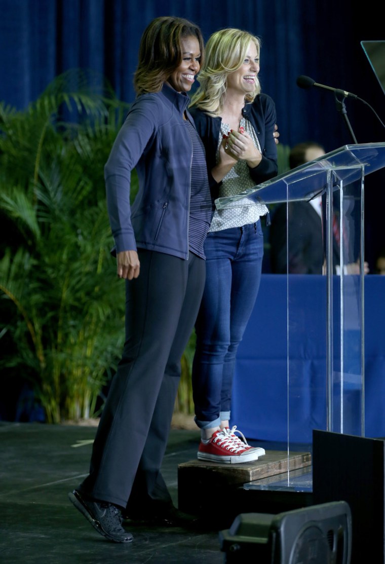 First Lady Michelle Obama stands on stage with actress  Amy Poehler, during a visit to the Gwen Cherry Park NFL/YET Center on February 25, 2014 in Mia...