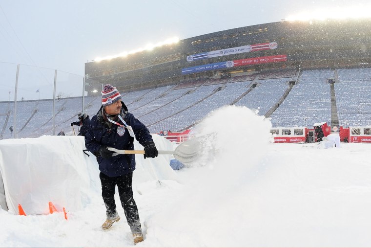 An ice crew member shovels snow during the 2014 Bridgestone NHL Winter Classic on Wednesday at Michigan Stadium in Ann Arbor.