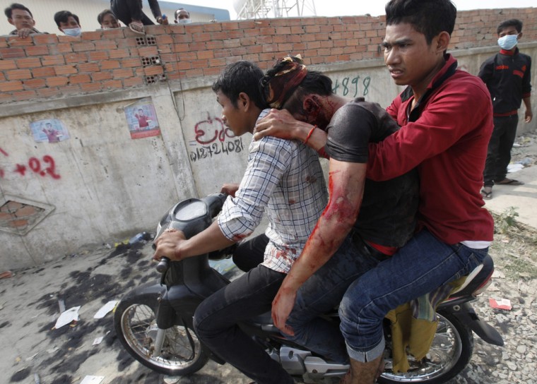 Garment workers assist an injured man after clashing with police officers during a protest in Phnom Penh on Jan. 3.