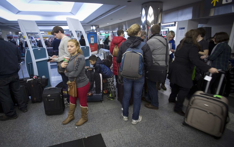 People line up for information about their flights at La Guardia airport in New York on Monday, Jan. 6, 2014. Arctic temperatures are affecting travel by plane and train and foot.