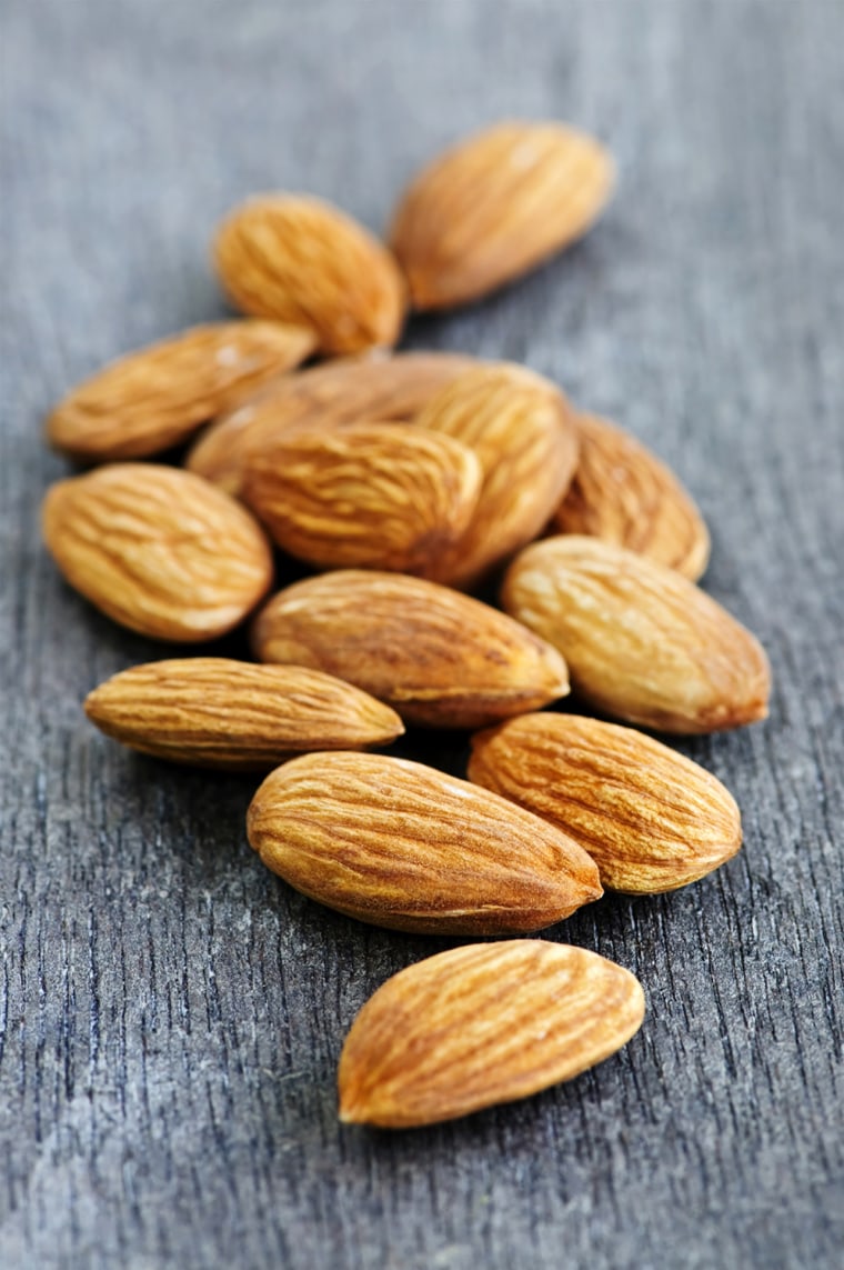 Raw almonds in a pile on wooden surface