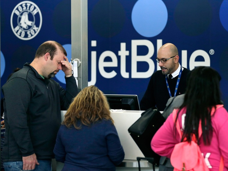 A traveler holds his forehead while waiting to rebook a canceled JetBlue flight on Jan. 6 in Boston. JetBlue halted operations in Boston, New York and New Jersey later in the afternoon, to rest crews and give it time to service aircraft, due to flight delays and cancellations.