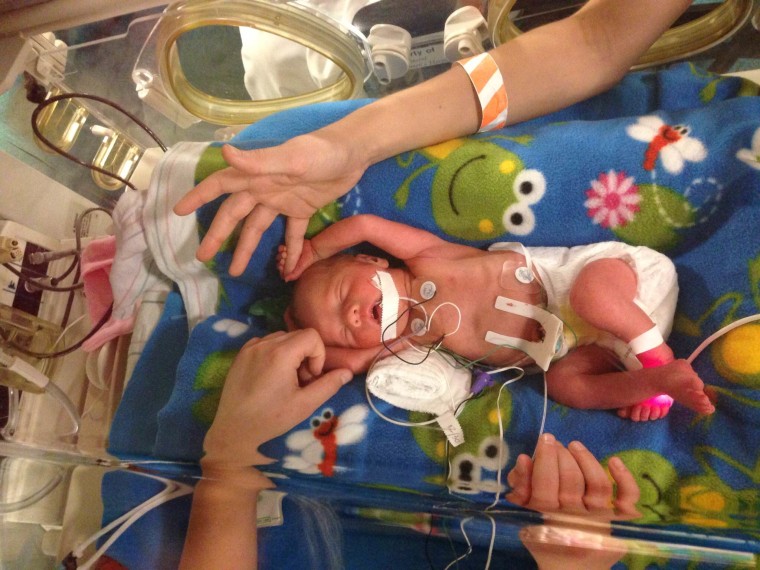 Big siblings Caleb and Kaitlyn touch tiny Cassidy, one of three identical triplet girls born Dec. 30, in the NICU.