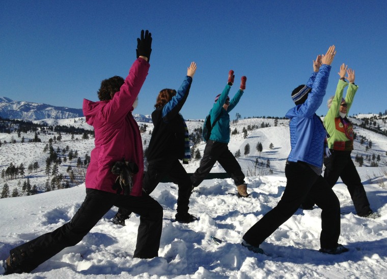 Snowshoers practice a \"warrior\" pose during a snowga session in Chelan, Wash.