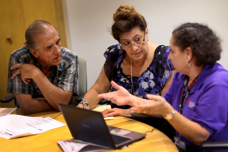 MIAMI, FL - OCTOBER 08: Affordable Care Act navigator Nini Hadwen (R) speaks with Jorge Hernandez (L) and Marta Aguirre as they shop for health insur...