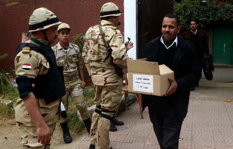 A box full of ballots is carried near Egyptian soldiers standing guard outside a school in Cairo that will be used as a polling station on Tuesday and Wednesday.