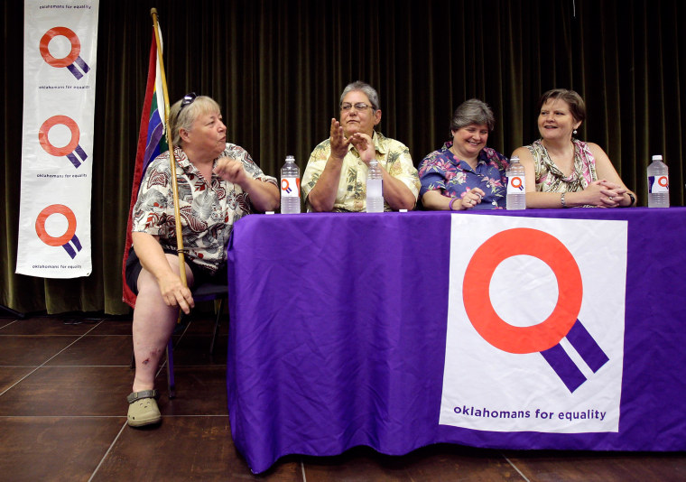Married partners Gay Phillips (with Pride flag) and Sue Barton, along with unmarried partners Sharon Baldwin and Mary Bishop, pictured at a June panel discussion, brought the suits that were upheld Tuesday.