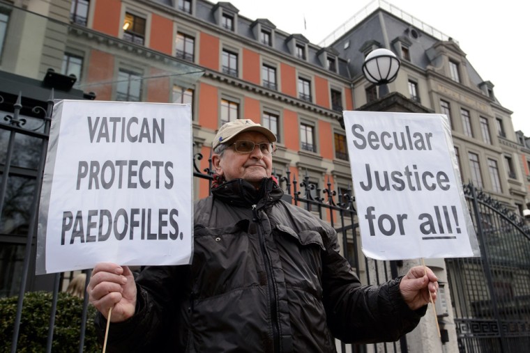 A man holds placards during a demonstration against the Holy See outside the headquarters of the committee hearing.