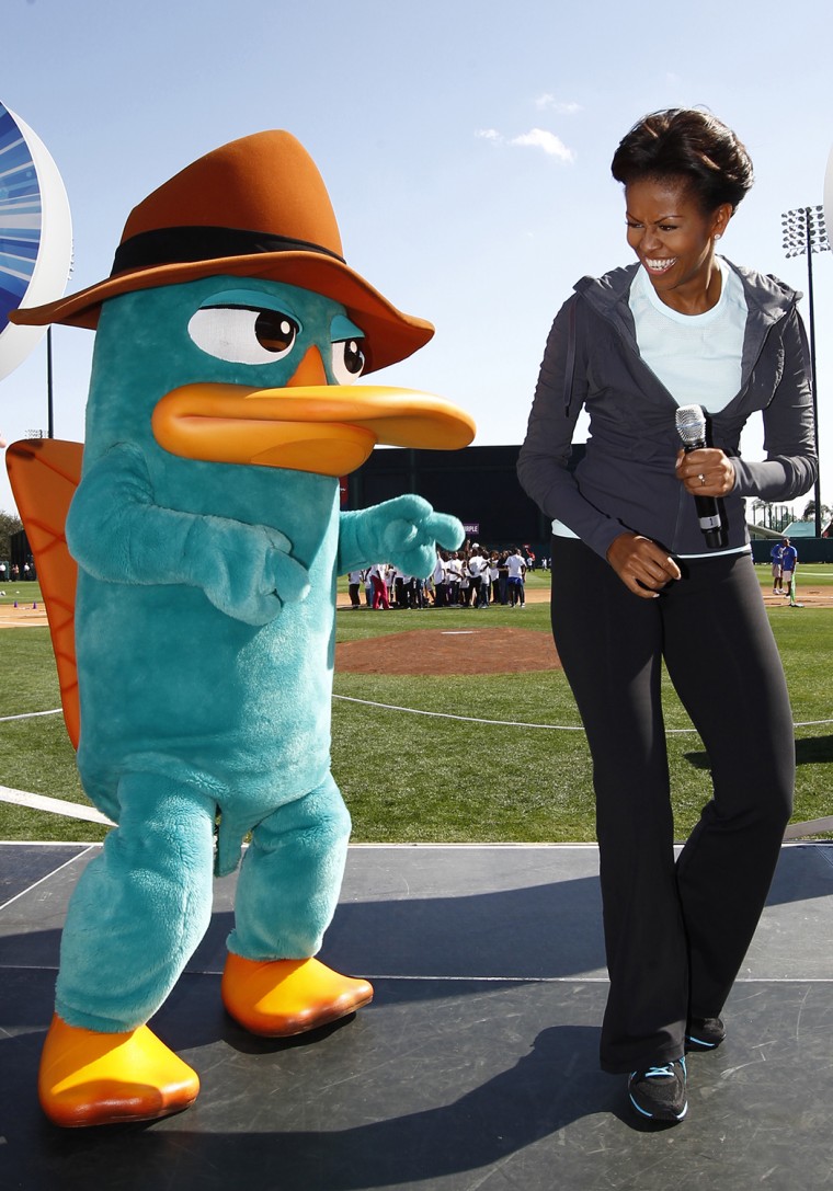 U.S. First Lady Michelle Obama laughs next to Perry the Platypus from the children's TV show \"Phineas and Ferb\", during a \"Let's Move!\" faith and comm...