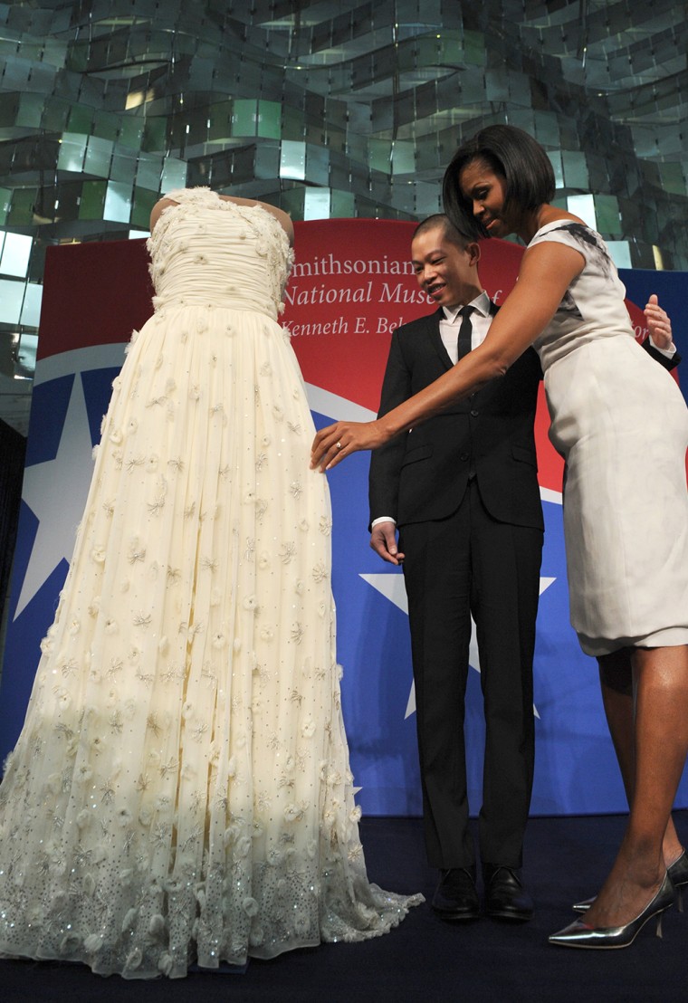US First Lady Michelle Obama (R) touches her 2009 inaugural gown as the designer of Mrs. Obamaâ€™s inaugural dress, Jason Wu, looks on during a ceremo...