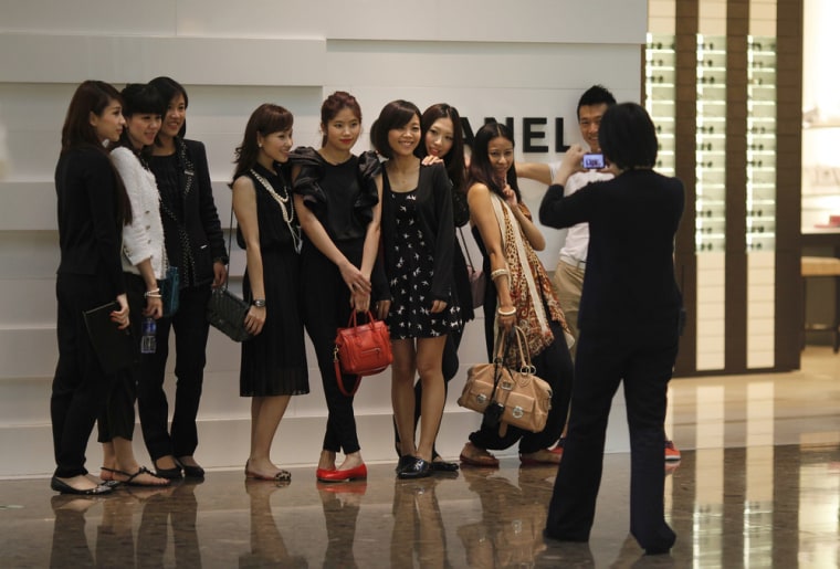Here today, gone tomorrow. Shoppers pose for a picture in front of a Chanel luxury boutique at the IFC Mall in Shanghai.